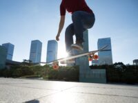 Asian woman skateboarder skateboarding in modern city