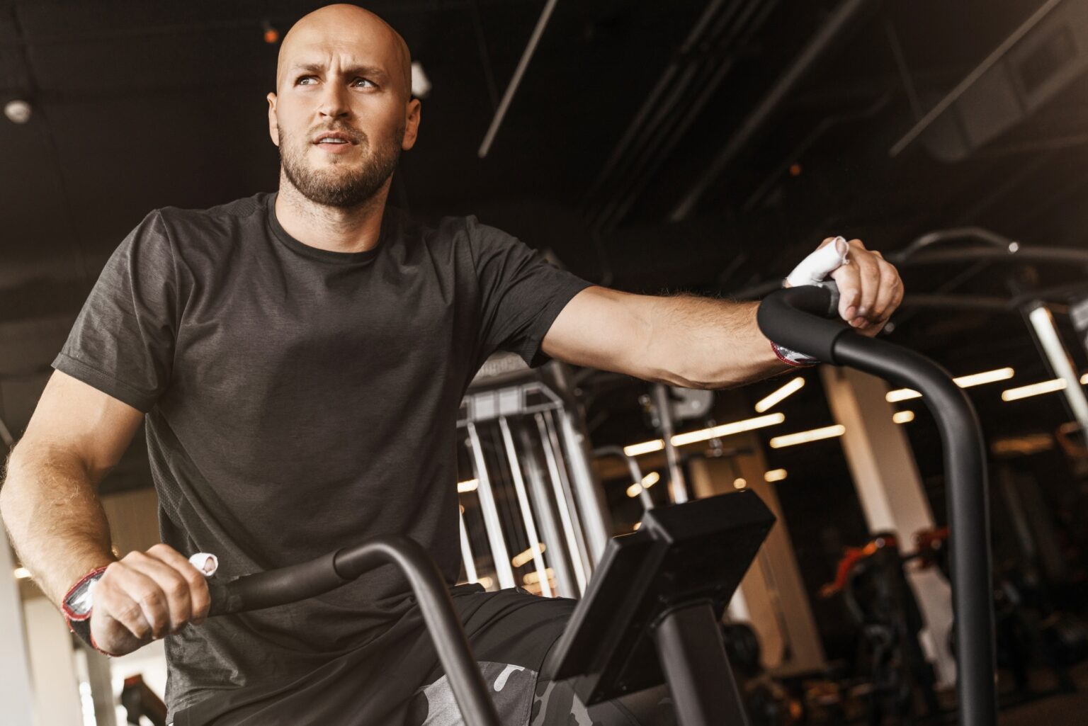 Fitness male using air bike for cardio workout at gym