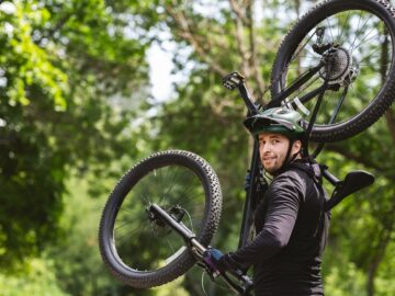 Sportsman holding his bike up on the forest path
