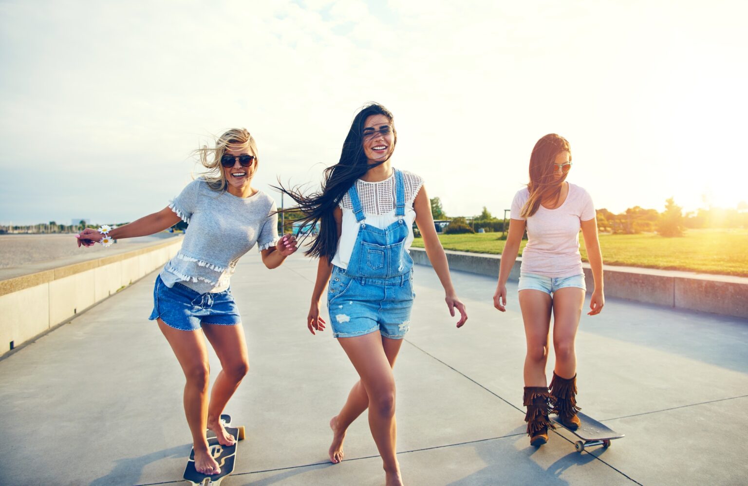 Three young woman skateboarding at the beach