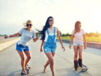 Three young woman skateboarding at the beach