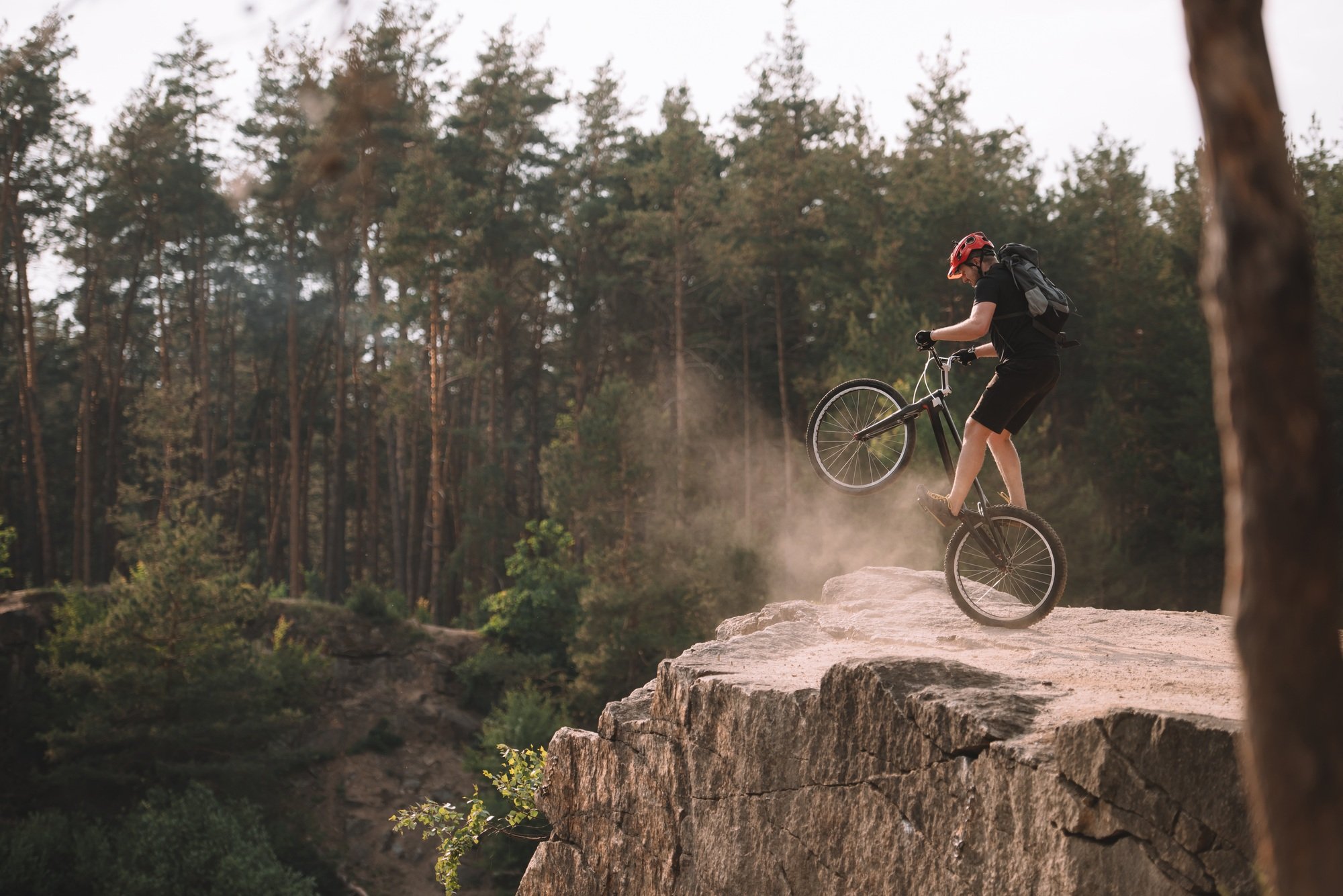 trial biker balancing on back wheel on rocks outdoors