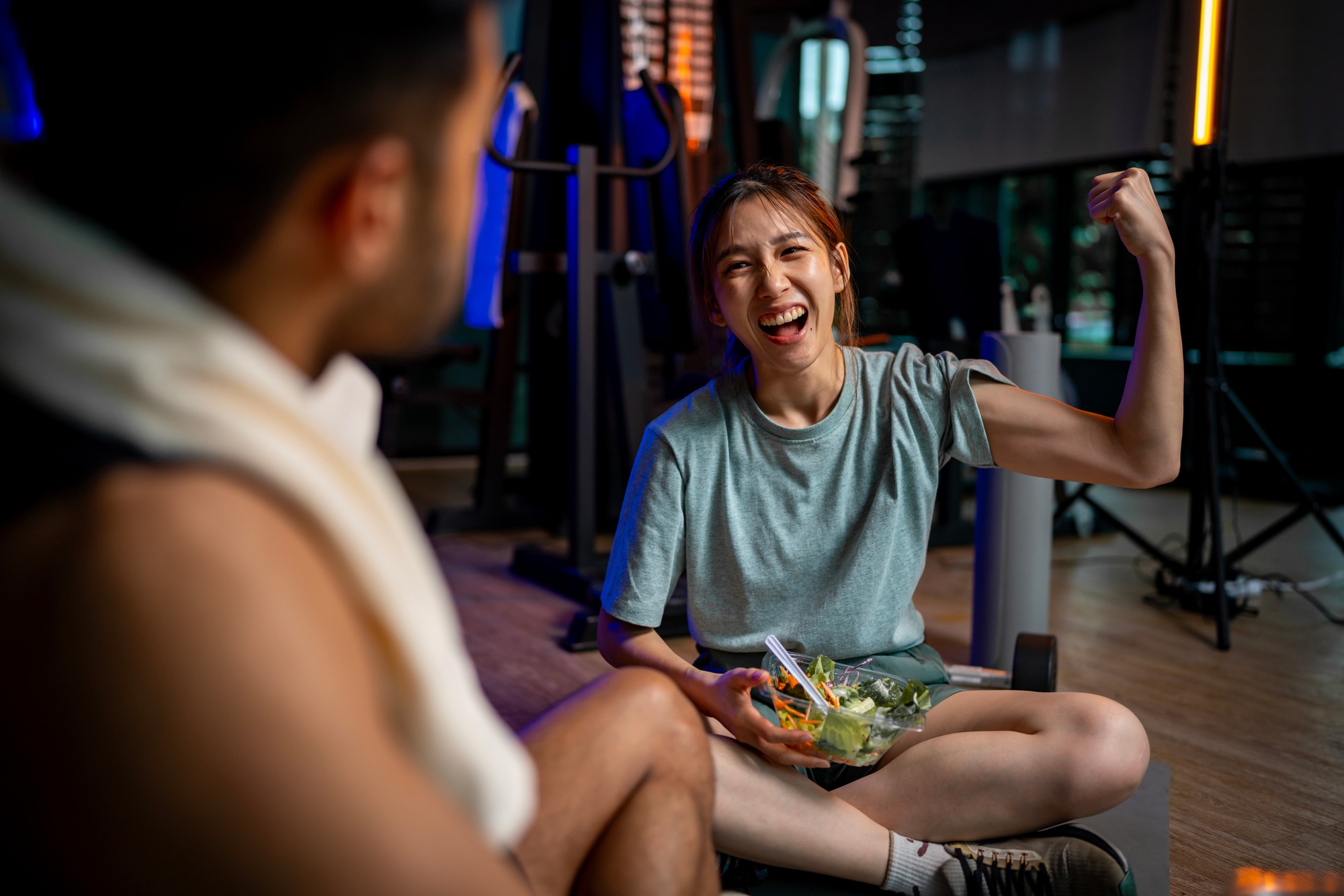 Two men and women are eating a vegetable salad together after exercising.