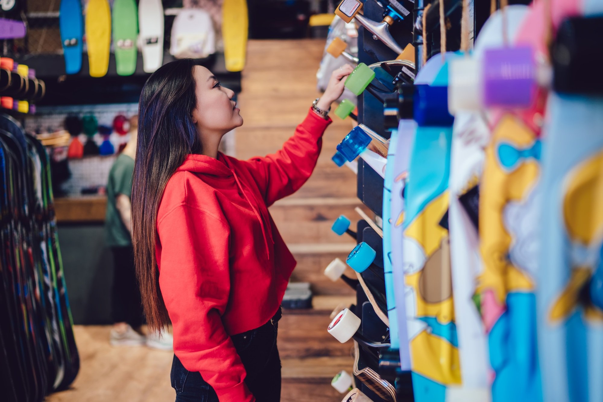 youthful Chinese hipster girl spending day for buying skateboard and practicing hobby skills