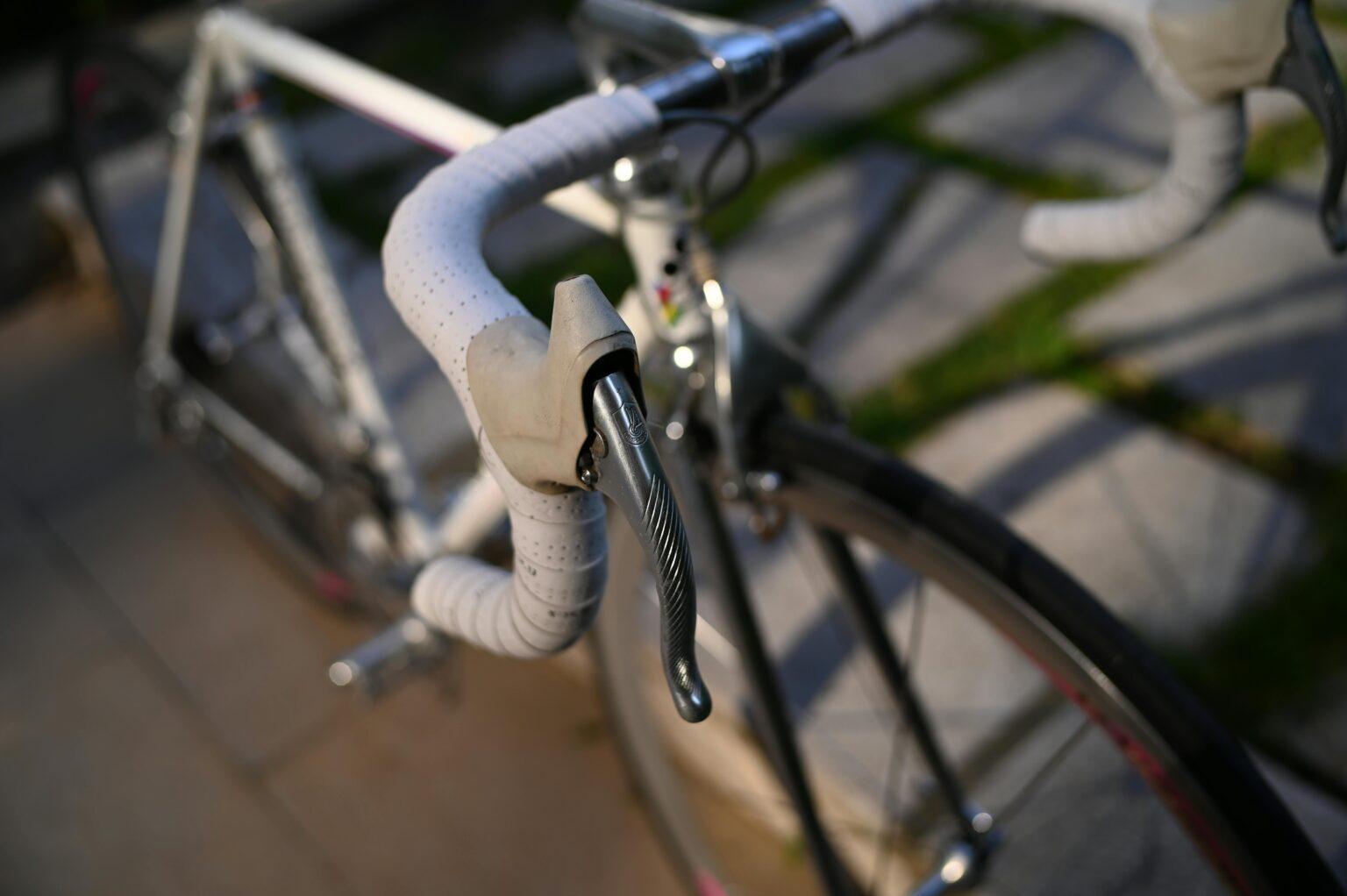 Comparaison des niveaux de groupes SRAM et Shimano : quel choix pour votre vélo ? Detailed focus on a road bike's handlebars with sunlight highlighting the textures.