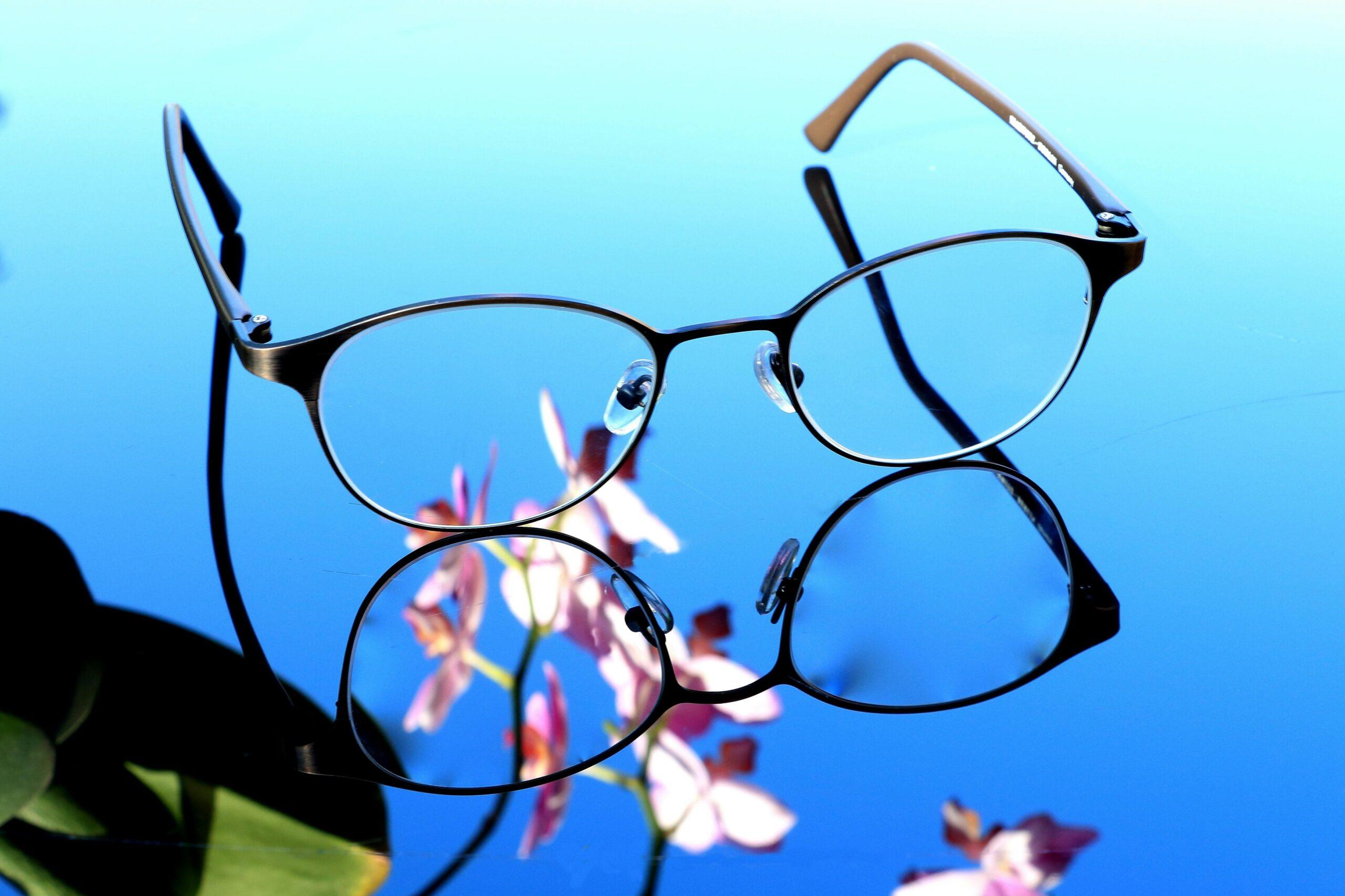 guide des couleurs et teintes des lentilles de lunette Von Zipper Stylish eyeglasses on reflective surface with orchid blossoms. Perfect for design inspiration.