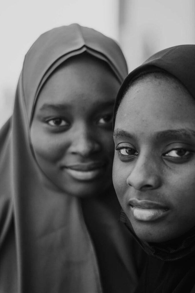 Black and white portrait of two women wearing hijabs, showcasing cultural identity and connection.