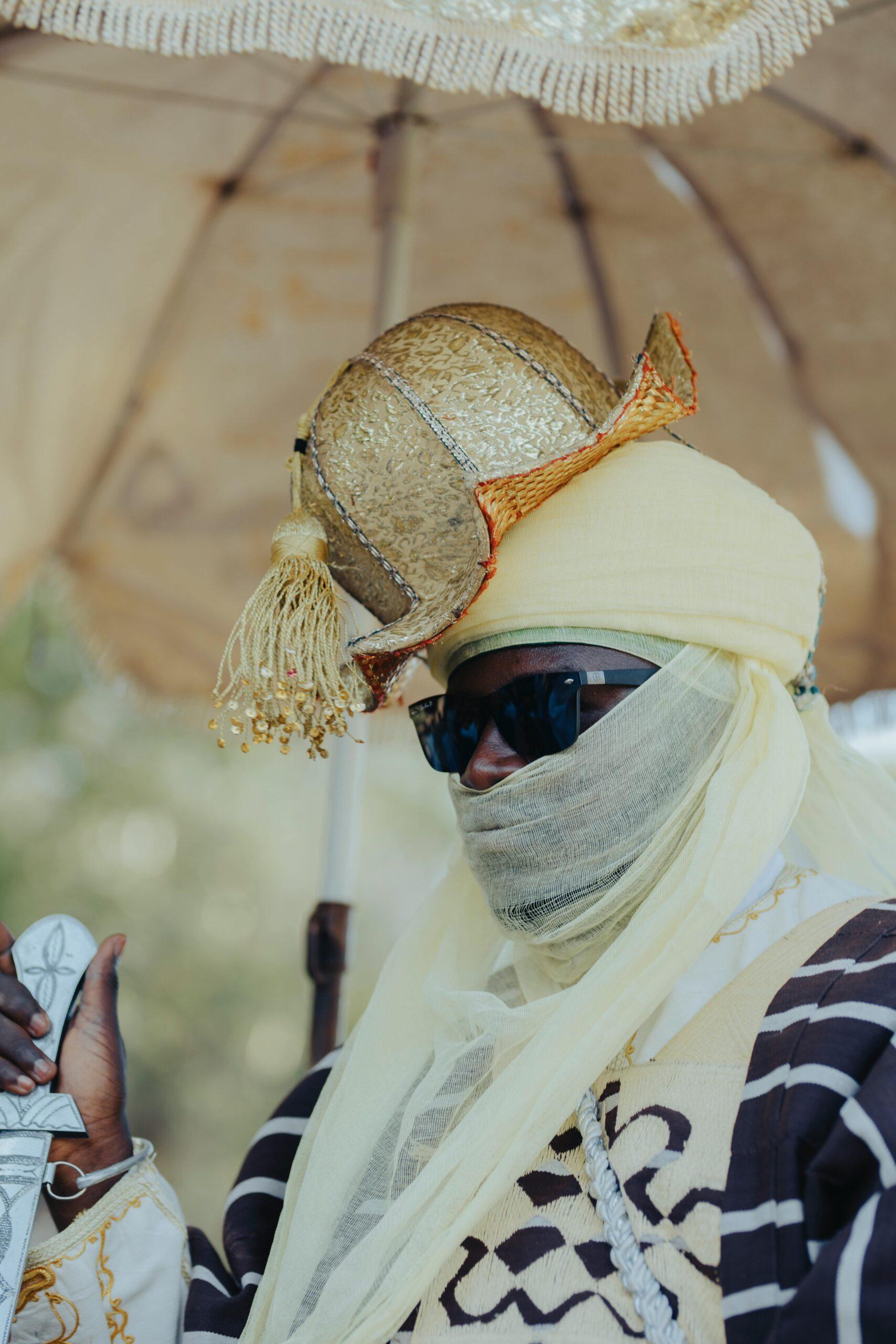 guide des couleurs et teintes des lentilles de lunettes de soleil pour espion A person in traditional African attire with a gold ornate headpiece and umbrella.