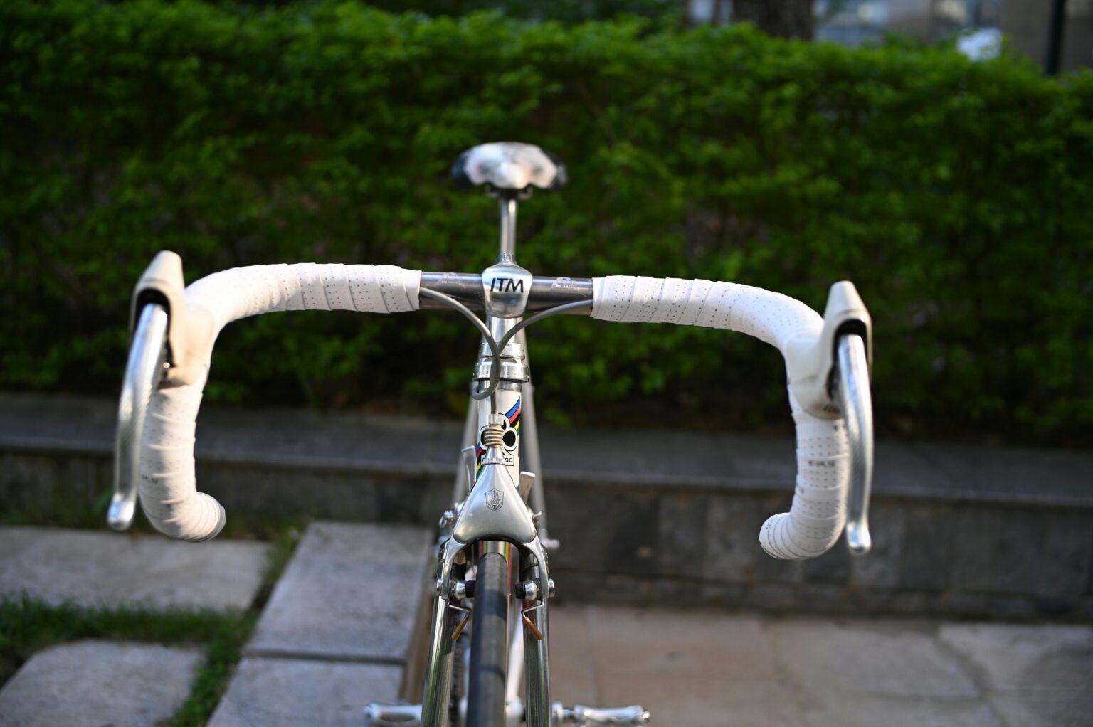 Detailed view of classic road bicycle handlebars with white tape outdoors.